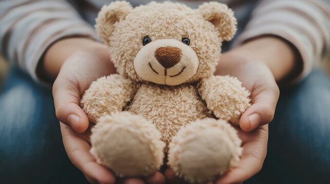 A person is holding a teddy bear - Powered by Adobe