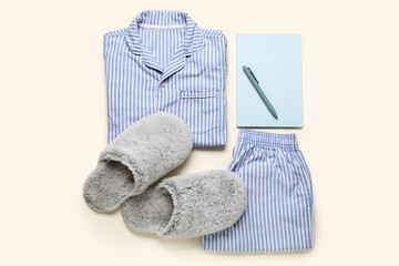 Composition with stylish female pajamas, slippers, notebook and pen on color background