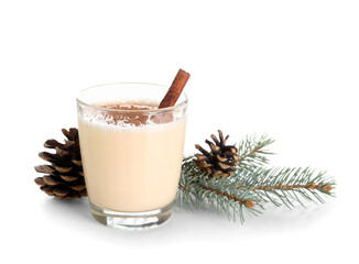 Glass of tasty eggnog cocktail with cinnamon, Christmas tree branch and pine cones on white background