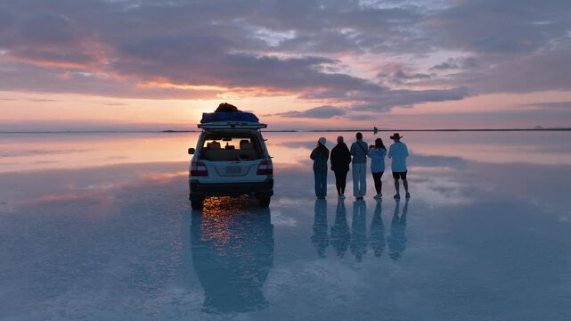 Drone Circles Around People Watching Sunrise in Reflective Uyuni Salt Flat, Bolivia