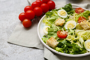 Plate with tasty Caesar salad and tomatoes on grey background, closeup