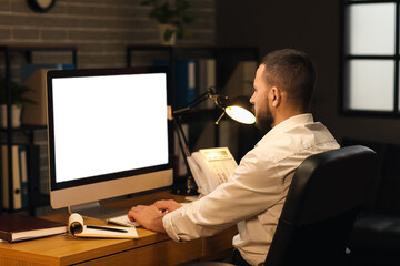 Young businessman working with blank computer in office at night