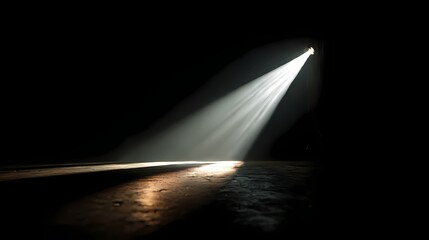 A beam of light cuts through darkness, illuminating a textured floor. The contrast highlights a sense of mystery and depth. Minimalist yet striking.