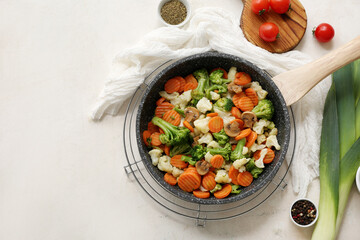 Frying pan with tasty roasted vegetables on white background