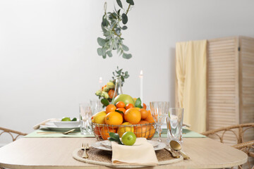 Basket with citrus fruits on beautiful served table in room. Closeup