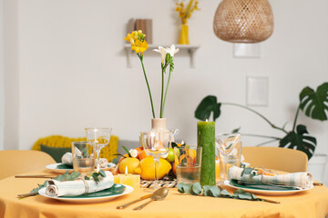 Beautiful table setting with citrus fruits, flowers and burning candles in room. Closeup
