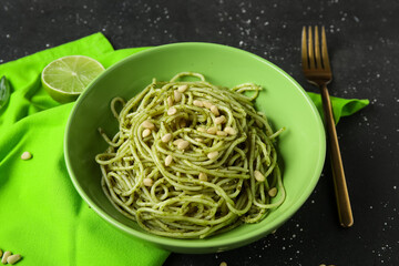 Plate of tasty pesto pasta with pine nuts on black grunge background