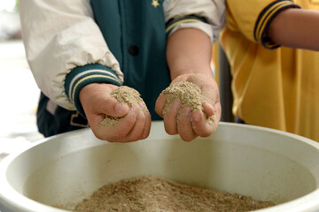 A toddler explores wood shavings in a plastic container to experience different textures. An...