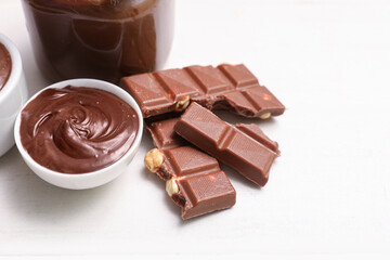 Bowl and jar of sweet chocolate spread on white wooden background
