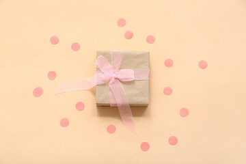 Gift box and pink confetti on beige background