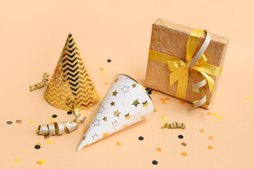 Party hats with gift box and confetti on brown background