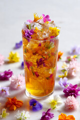Peach jasmine tea with edible flowers and ice