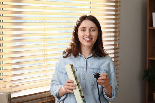 Young woman with extension cord and plug at home. National Day of Unplugging