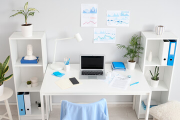 Interior of light office with workplace, shelf units and plants