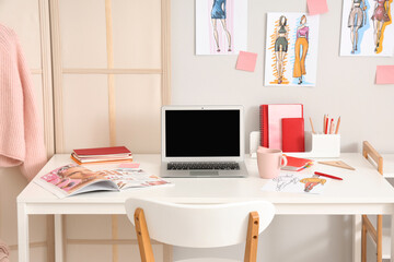 Fashion designer's workplace with blank laptop in office