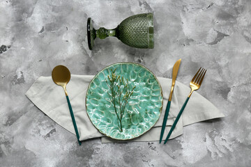 Beautiful table setting with golden cutlery and gypsophila flowers on grey grunge background