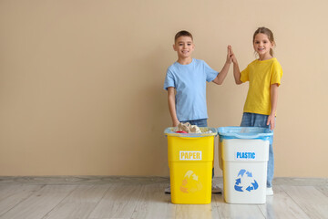 Cute children giving each other high-five with garbage containers near beige wall. Global Recycling...