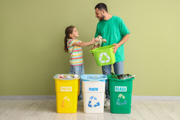 Father with his daughter sorting garbage near green wall. Global Recycling Day