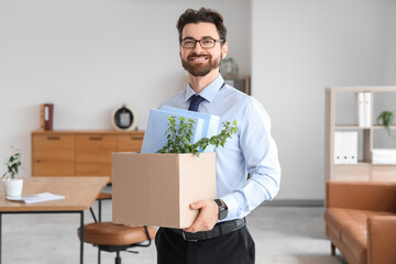 Happy fired young man holding box with his personal stuff in office
