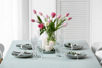 Beautiful table setting for Mother's Day celebration and vase with tulip flowers in dining room