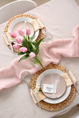 Beautiful table setting for Mother's Day celebration and vase with tulip flowers in dining room