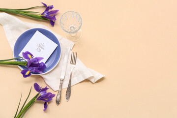 Obraz premium Beautiful table setting with greeting card and iris flowers on beige background. Mother's Day celebration