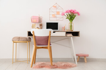 Interior of modern workplace with stools,  beautiful tulip flowers, laptop and stationery on table