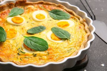 Delicious Easter egg tart with spinach leaves on black background, closeup