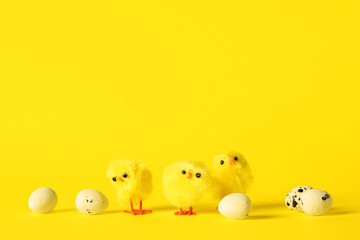 Easter eggs and baby chickens on yellow background