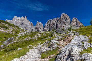 Dolomites, Alpi Dolomiti beautiful scenic mountain landscape under blue sky in summer. Rocky tower peak summits of the Alps on a sunny day. Alpine scenic view of the cliffs and climbing walls in Italy