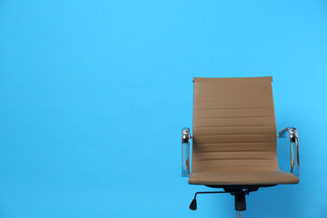 Comfortable office chair on light blue background, space for text