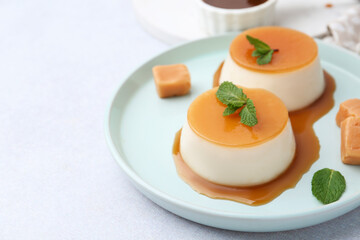 Tasty puddings with caramel sauce served on white table, closeup. Space for text