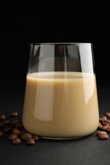 Coffee cream liqueur in glass and beans on black table
