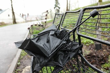 Broken umbrella on wet bench in park