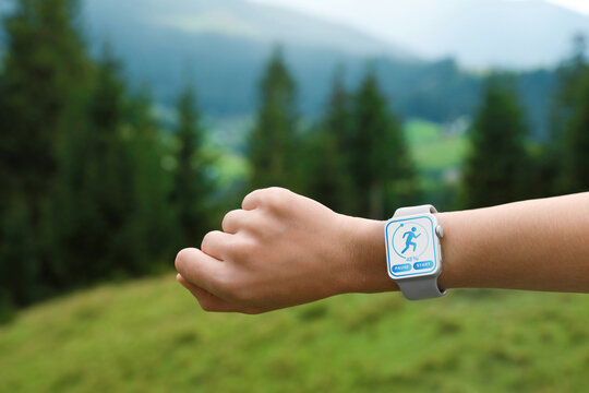 Woman checking smart watch with step counting app in wilderness, closeup