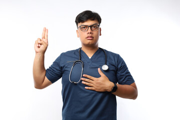 Young doctor wearing medical uniform over isolated background swearing with hand on chest and...