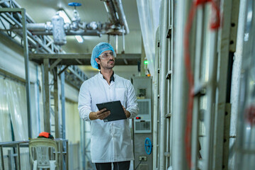 Factory technician inspecting an industrial tank with a clipboard, showcasing precision, quality...