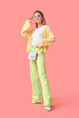 Stylish young woman in spring clothes on pink background