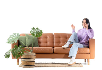Young woman talking by mobile phone on brown sofa against white background