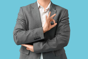 Businessman showing OK on blue background, closeup