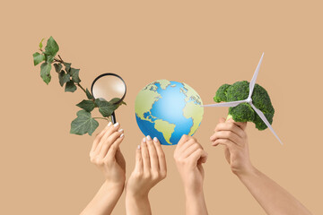 Female hands with plant, magnifier, paper Earth and wind turbine on beige background. Ecology concept