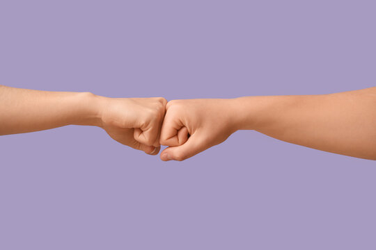 Hands bumping fists on lilac background