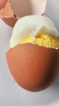 Peeled chicken eggs, showing the contents are yellow and white, on a white ceramic plate with protein inside