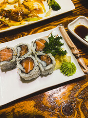 Sushi on a white plate on a wooden table in a restaurant