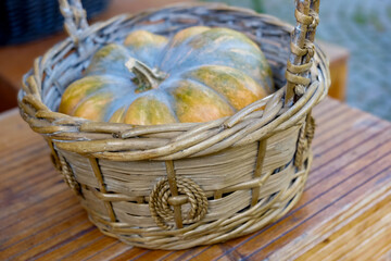 Pumpkin in a wicker basket on a wooden table. Outdoors decoration