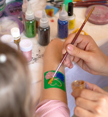 selective focus. decorative cosmetics for children and adults. holy Flash tattoo. Transfer tattoos for kids. master makes a girl a transfer temyporar glitter tattoo with sequins. childreay. Animators