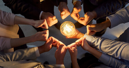 Close-up shot of business people in team and group showing thumbs up near light bulb, symbolizing creative idea and togetherness in a professional setting with focus on innovation.