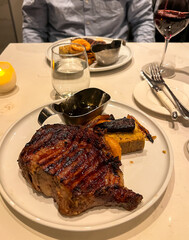 Grilled steak on a white plate with a glass of red wine