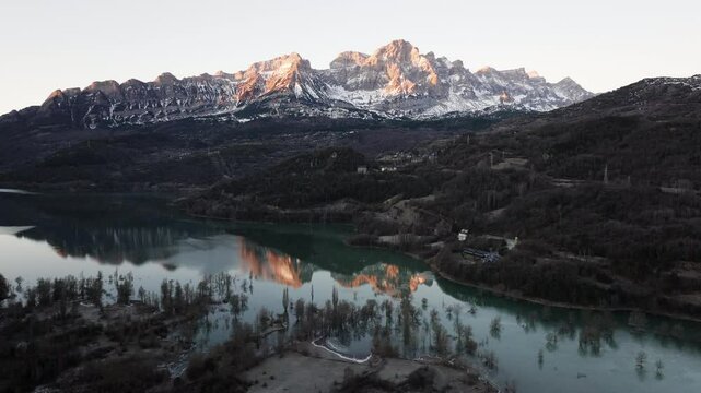 Aerial shot - Pena Telera mirroring peaceful waters during golden sunrise at Ibon de los Banos, artificial lake nestled in Tena Valley, Spanish Pyrenees