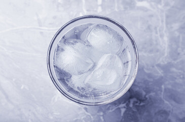 Glass of soda water with ice on marble table, top view